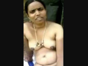 A Telugu middle-aged woman covertly strolls with a weapon outdoors